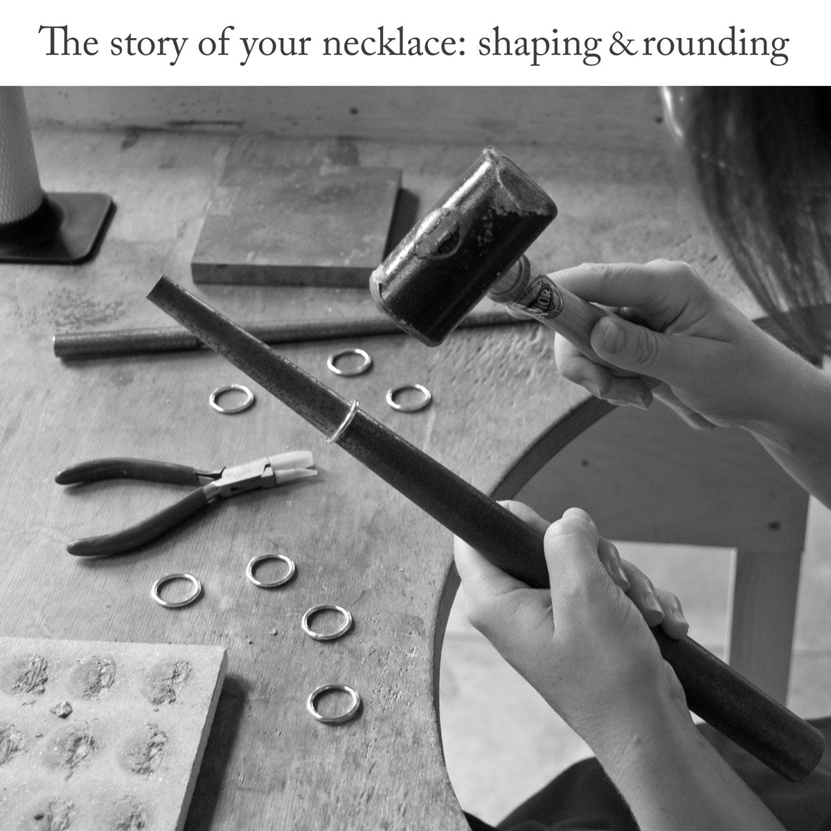 Close-up of silversmith sitting at a workbench using a mandrel and rawhide mallet to shape and round a thick piece of sterling silver wire with the headline text 'The story of your necklace: shaping and rounding'