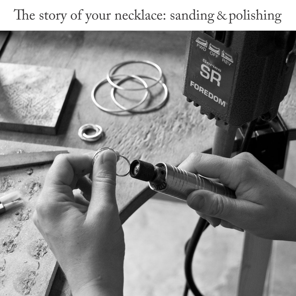 Craftsperson sanding and polishing jewellery with a Foredom tool over the surface of wooden work bench with the headline 'The story of your necklace: sanding and polishing'